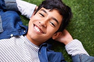 Boy lying in grass smiling